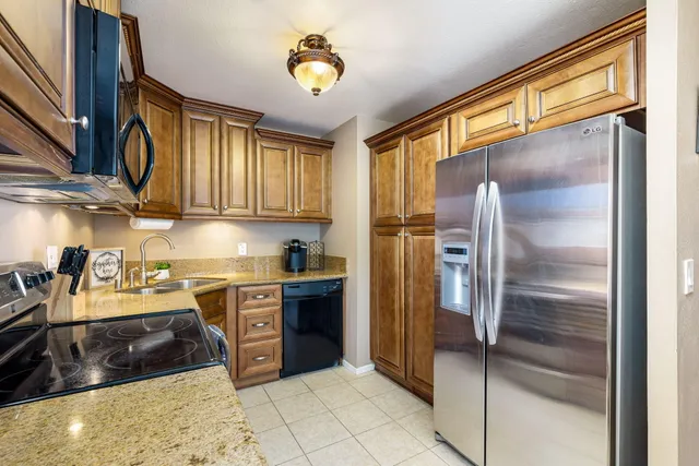 a kitchen with stainless steel appliances granite countertop a refrigerator a stove and a sink with dishwasher