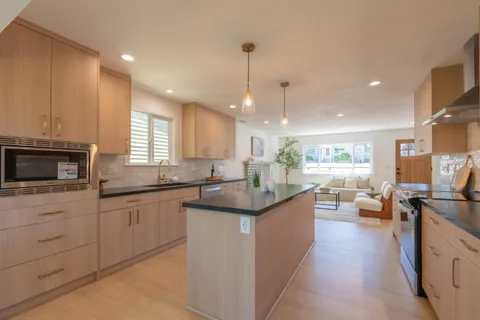 a kitchen with stainless steel appliances granite countertop a sink a stove and a wooden floors