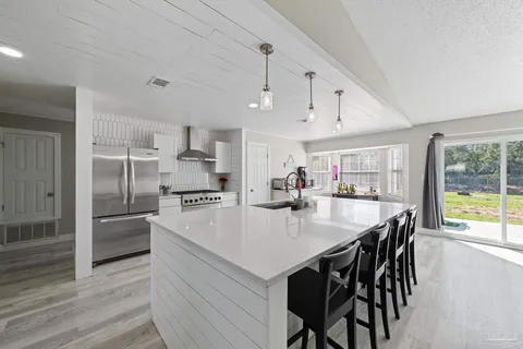 a kitchen with kitchen island a stove a table and chairs in it