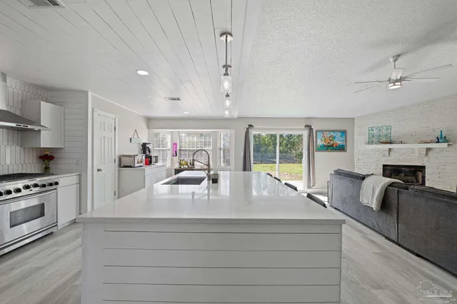 a large kitchen with kitchen island a large window a sink stainless steel appliances and cabinets