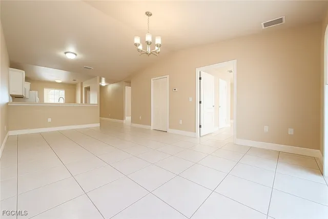 an empty room with kitchen and chandelier fan