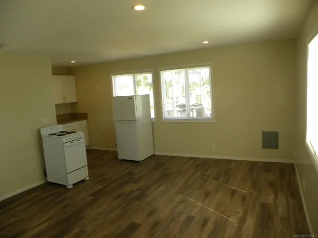a view of an empty room with a window and wooden floor