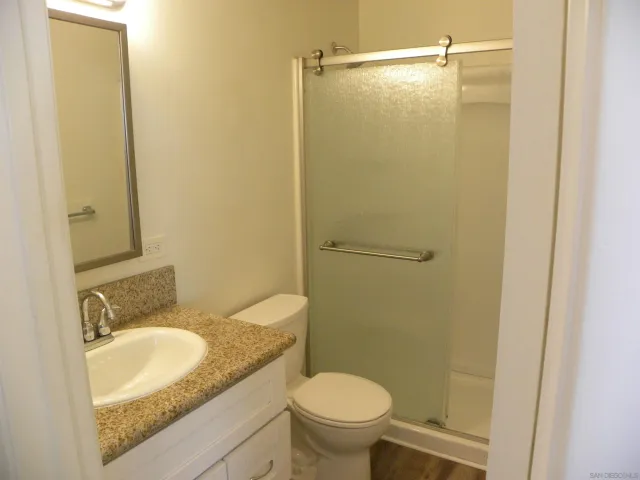 a bathroom with a granite countertop sink toilet and shower