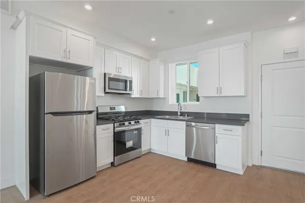 a kitchen with stainless steel appliances granite countertop a refrigerator stove a sink and white cabinets