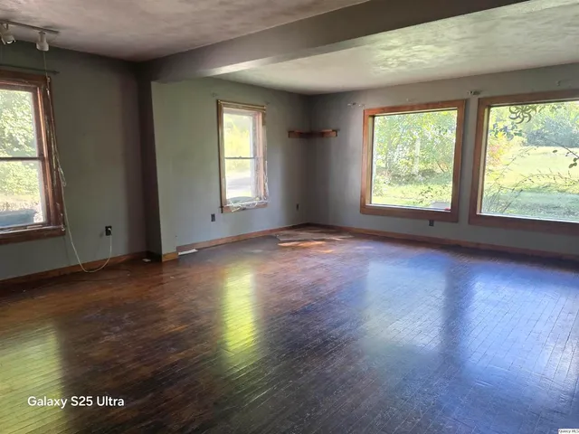 an empty room with wooden floor and windows