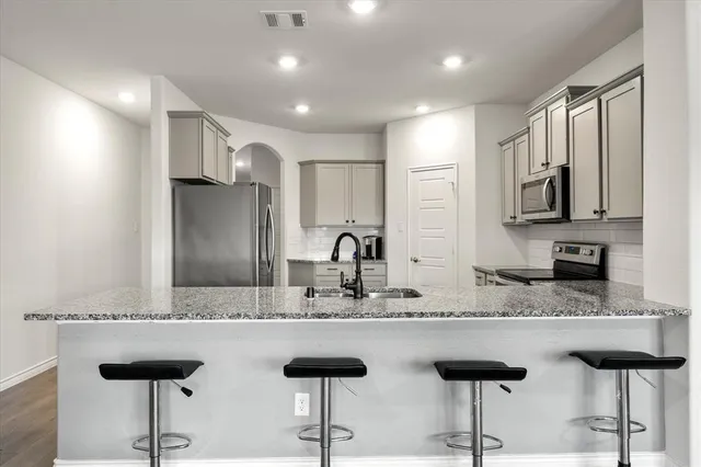 a kitchen with stainless steel appliances granite countertop a sink a stove a refrigerator and cabinets