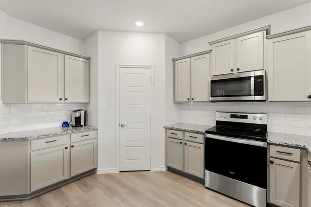 a kitchen with white cabinets and stainless steel appliances
