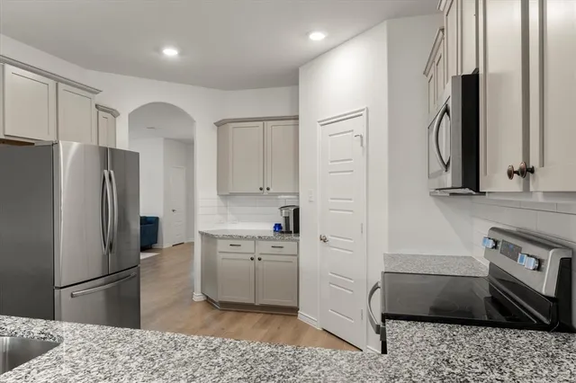 a kitchen with stainless steel appliances granite countertop a refrigerator a stove and a sink