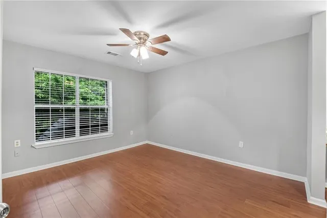 a view of an empty room with wooden floor and a window