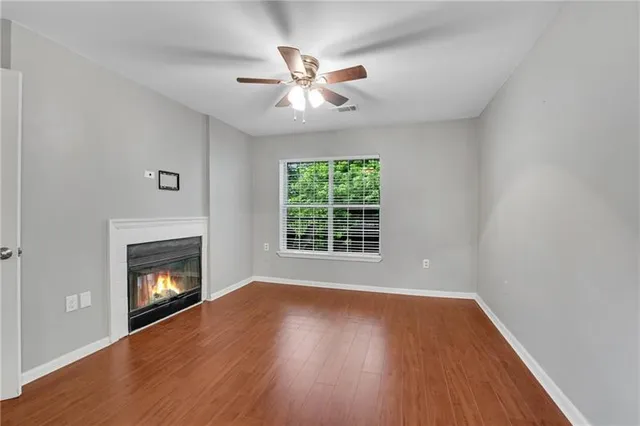 a view of an empty room with wooden floor fireplace and a window