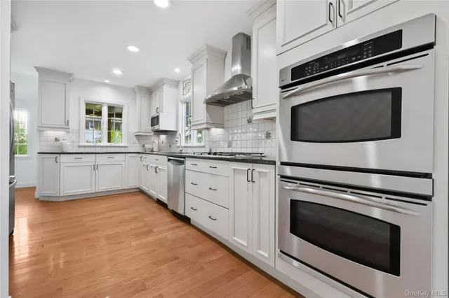 a kitchen with stainless steel appliances white cabinets and a stove top oven