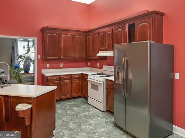 a kitchen with stainless steel appliances granite countertop a refrigerator a stove and a sink with wooden cabinets