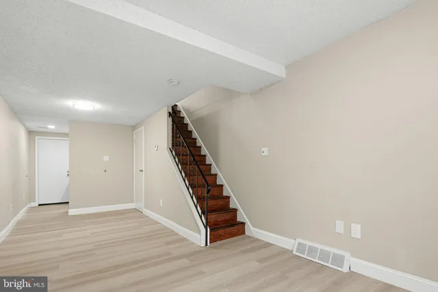 a view of an empty room with wooden floor and window