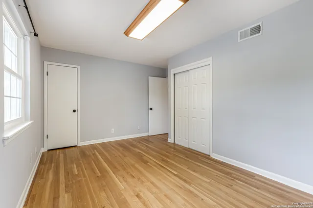 a view of empty room with wooden floor and fan