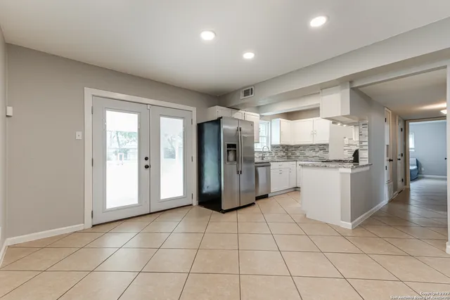 a kitchen with a refrigerator and white cabinets