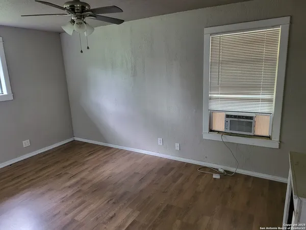 a view of an empty room with a window and wooden floor