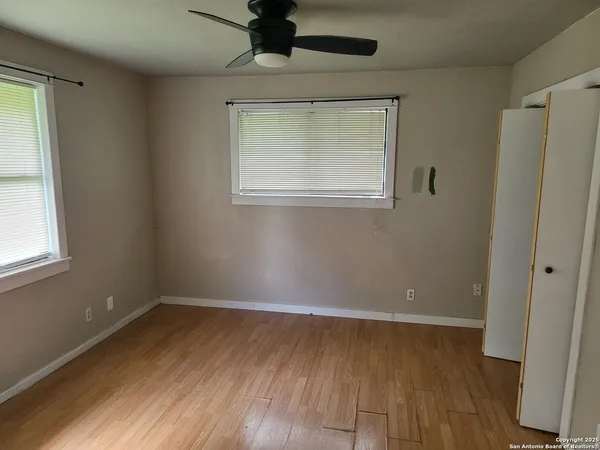 an empty room with wooden floor and windows