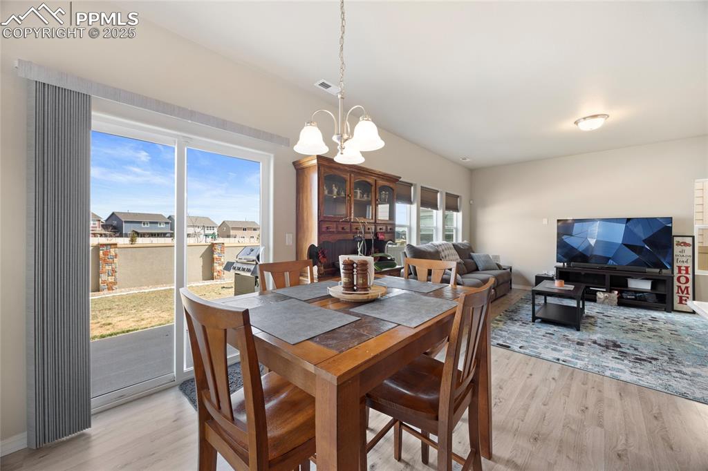 4536 Gneiss Loop Colorado Springs, CO 80938 - Photo 7 of 24 a dining room with furniture a chandelier and wooden floor