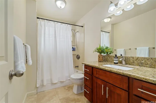 a bathroom with a granite countertop sink a toilet and shower
