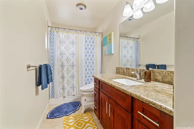 a bathroom with a granite countertop sink a toilet a mirror and shower curtain