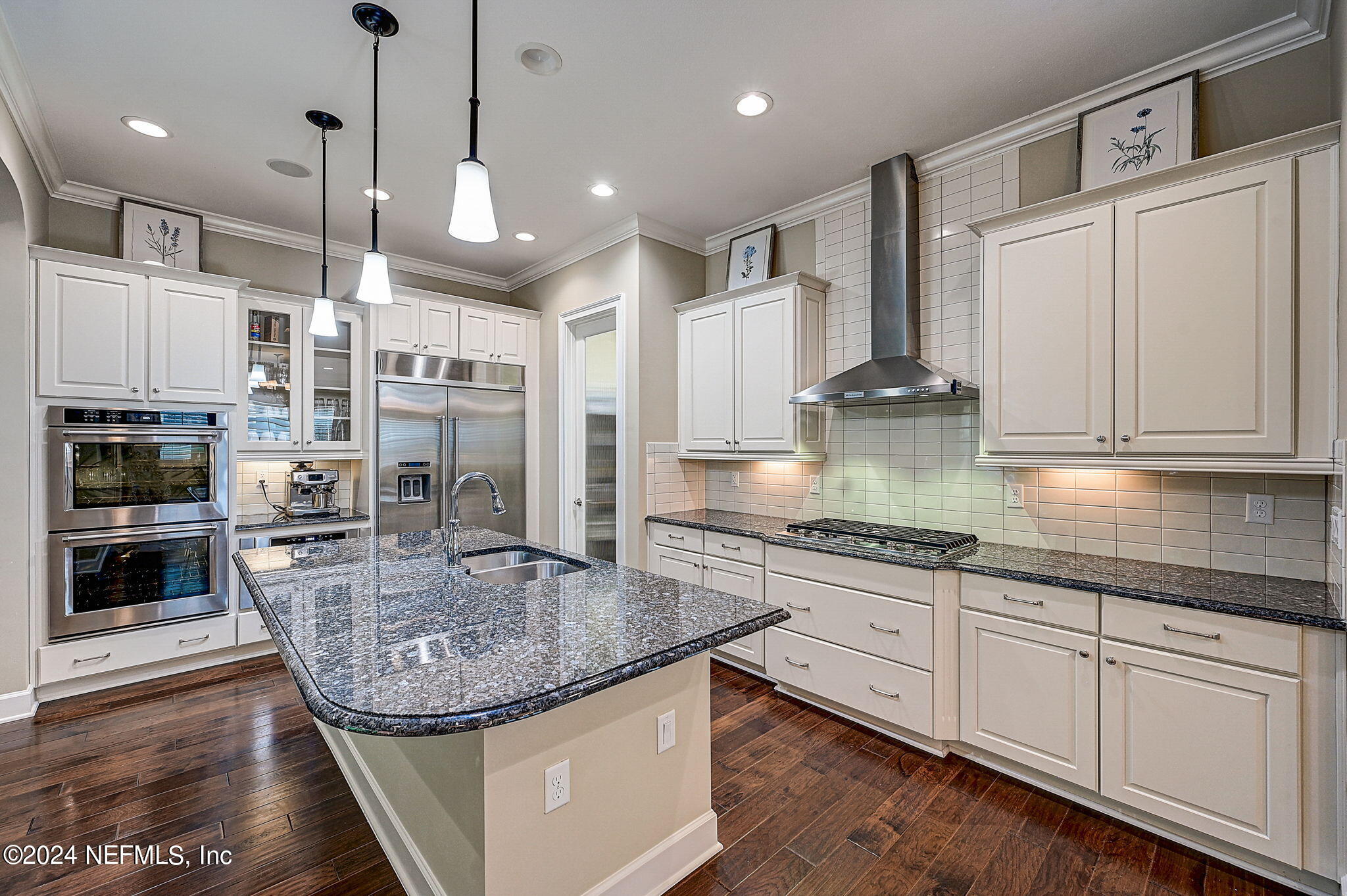 a kitchen with stainless steel appliances granite countertop a sink a stove and a wooden floors