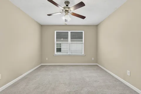 an empty room with a window and a fan
