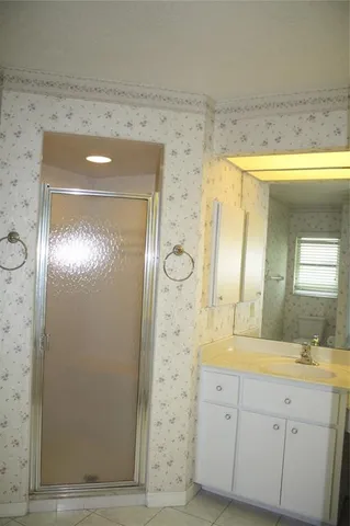 a bathroom with a granite countertop sink a mirror and a shower