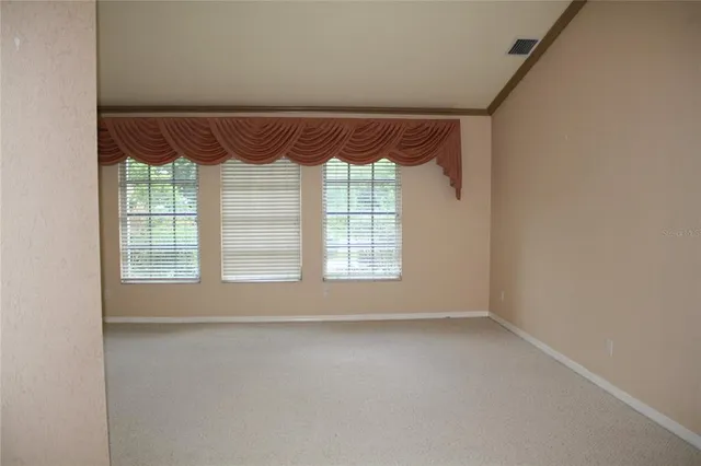 a view of empty room with wooden floor and a window