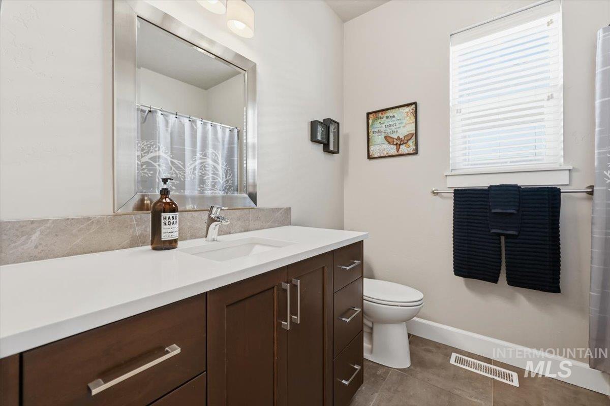 1303 West Brando Street Meridian, ID 83646 - Photo 7 of 49 Bathroom featuring a dark wood-finish vanity with white countertop, undermount sink, and brushed nickel hardware
