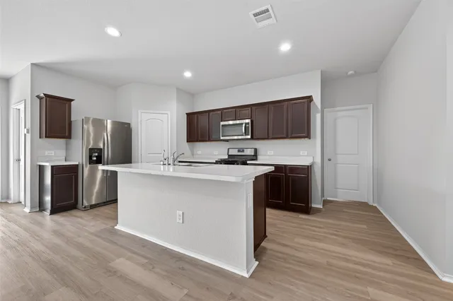 a kitchen with granite countertop a refrigerator and a stove top oven