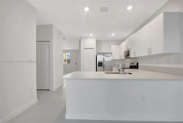 a large white kitchen with kitchen island a sink a refrigerator and a stove
