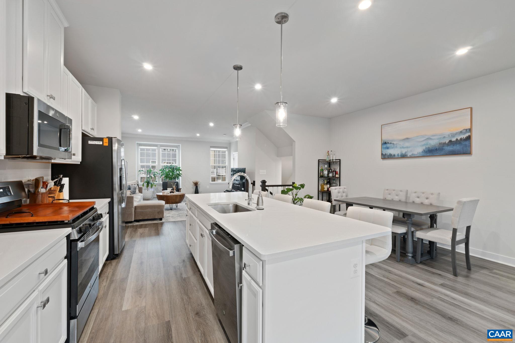 2402 Crescent Way Charlottesville, VA 22911 - Photo 14 of 27 Modern kitchen featuring large center island with seating, stainless steel appliances, white cabinetry, and open flow to dining and living areas.