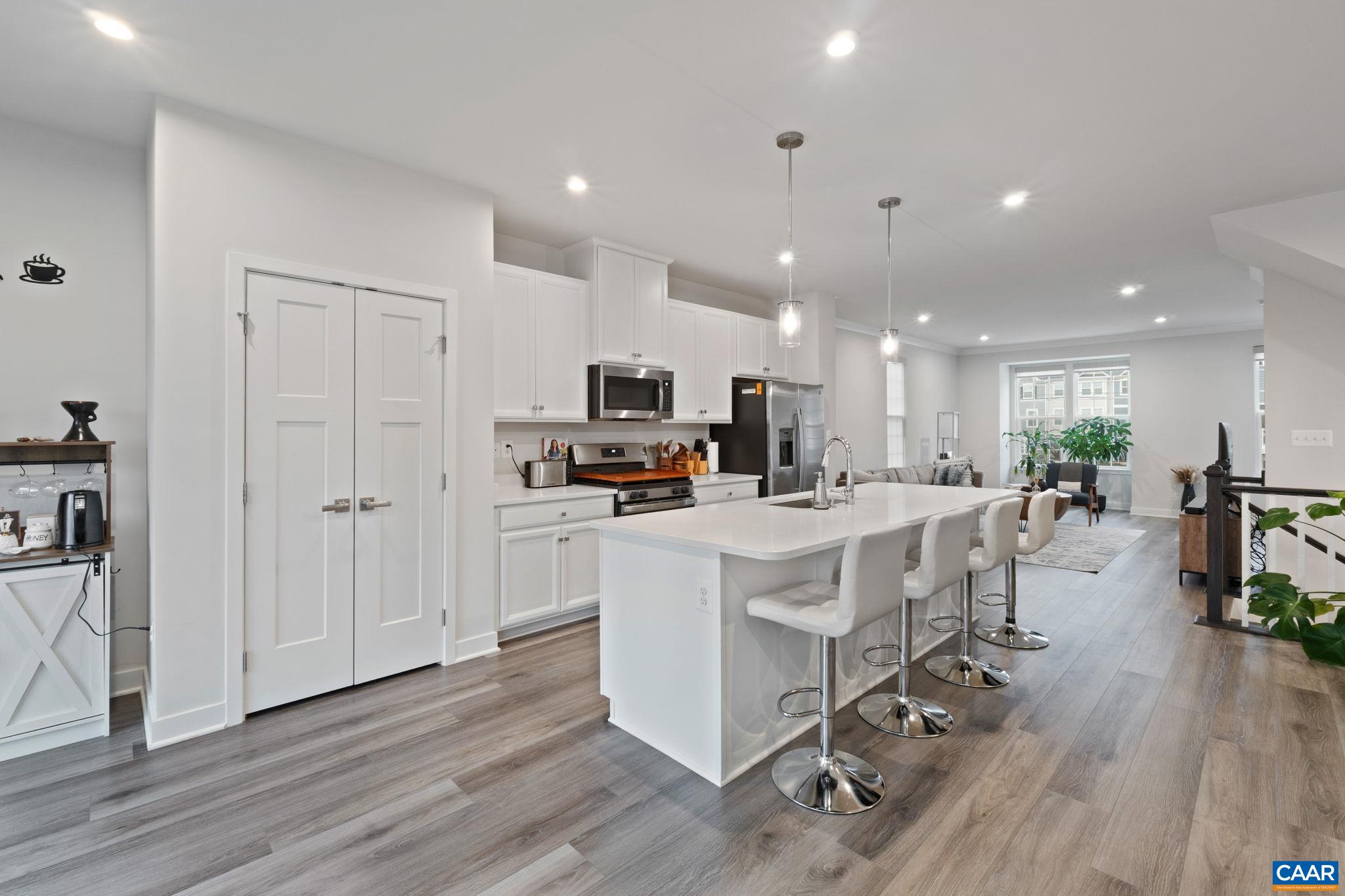 2402 Crescent Way Charlottesville, VA 22911 - Photo 17 of 27 Bright, open-concept kitchen showcasing a spacious island with seating, white cabinetry, stainless steel appliances, and seamless flow into the living area—perfect for entertaining.