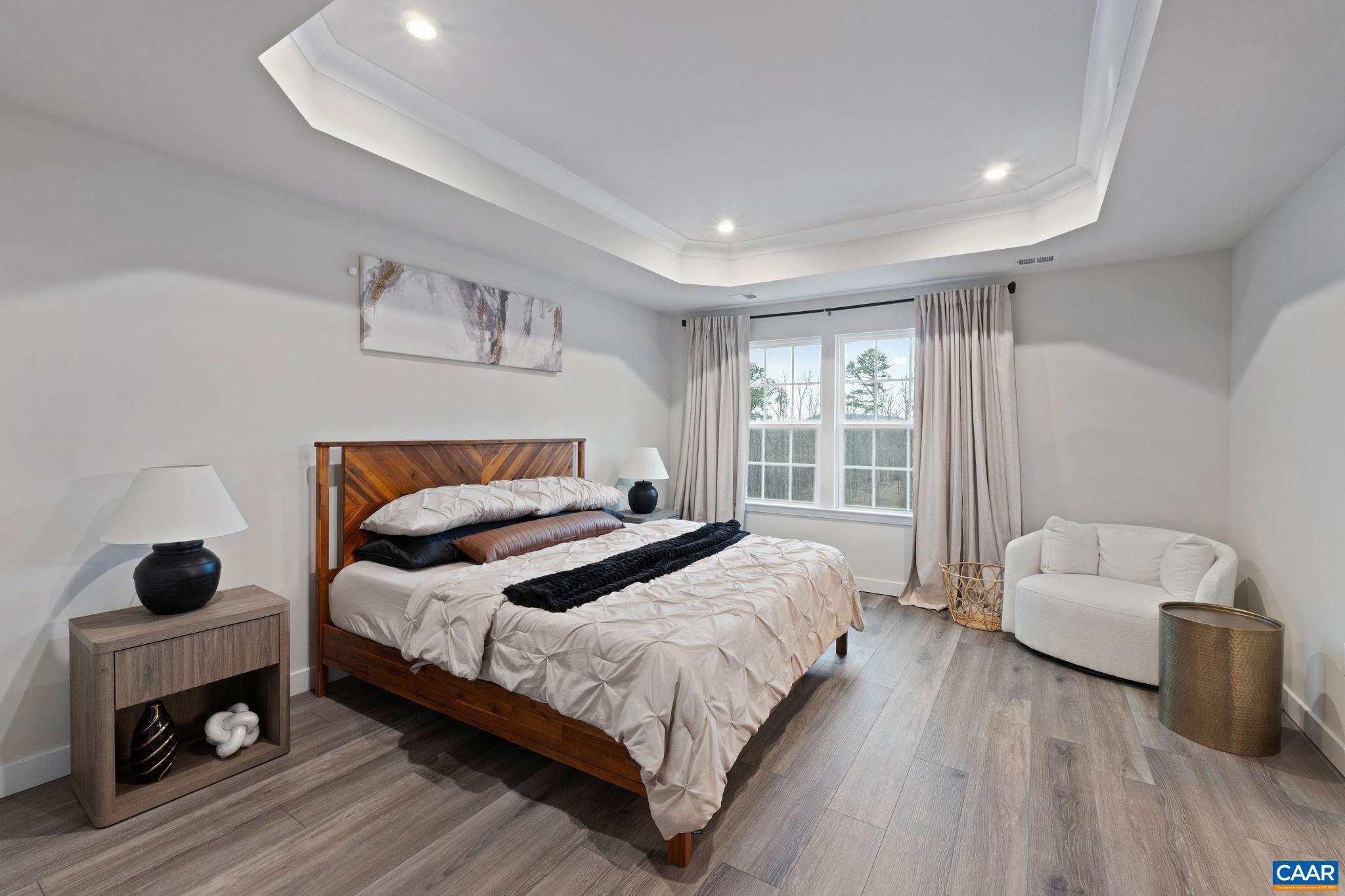 2402 Crescent Way Charlottesville, VA 22911 - Photo 22 of 27 Spacious primary bedroom featuring tray ceiling detail, large windows for natural light, and ample space for a sitting area—creating a comfortable and inviting retreat.