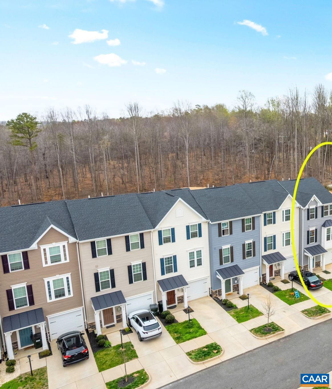 2402 Crescent Way Charlottesville, VA 22911 - Photo 26 of 27 Aerial view of the home highlighting its position within the community, featuring a one-car garage, private driveway, and a row of modern townhomes backing to a wooded area for added privacy.