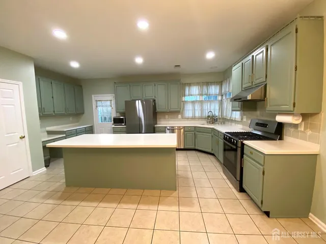 a large kitchen with kitchen island a stove a sink a counter top space and cabinets