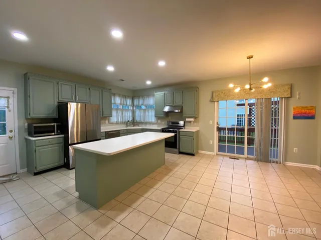 a large kitchen with kitchen island a large counter top stainless steel appliances and cabinets