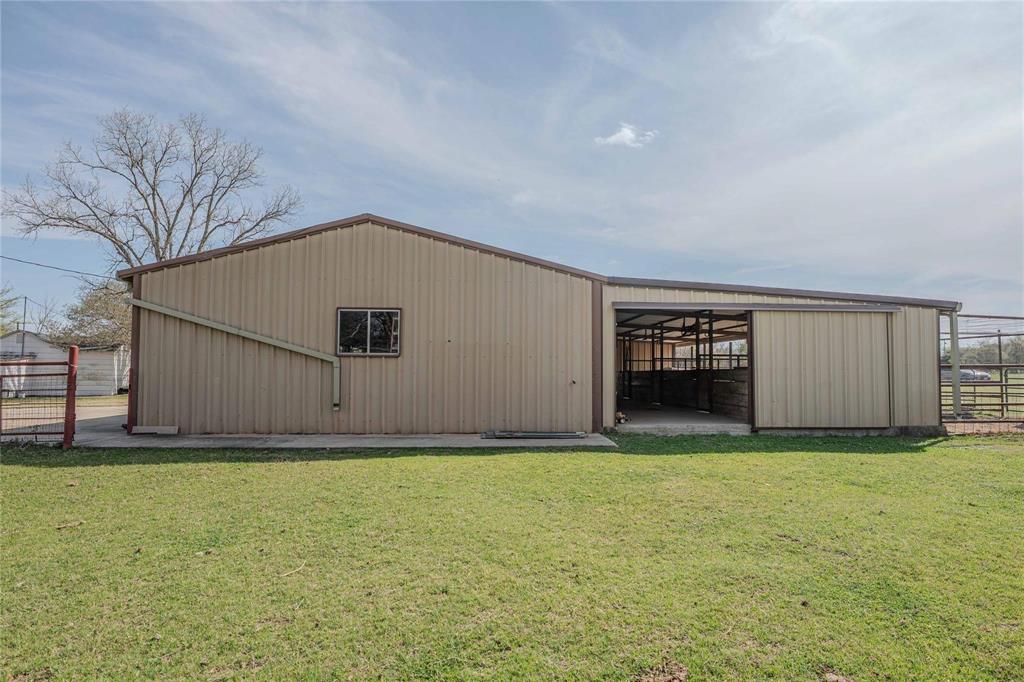 900 Silver Creek Azle Road Azle, TX 76020 - Photo 18 of 27 Metal-sided barn featuring a pitched roofline, an interior open bay with stalls, an exterior sliding door, a side window, and a rain gutter system