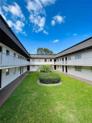 a view of a big yard with plants and large trees