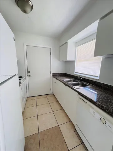 a kitchen with granite countertop a refrigerator and a stove top oven