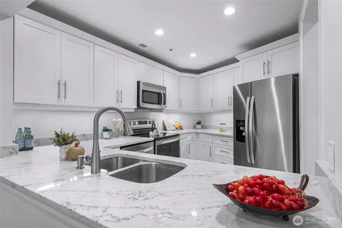 a kitchen with stainless steel appliances granite countertop a sink refrigerator and microwave