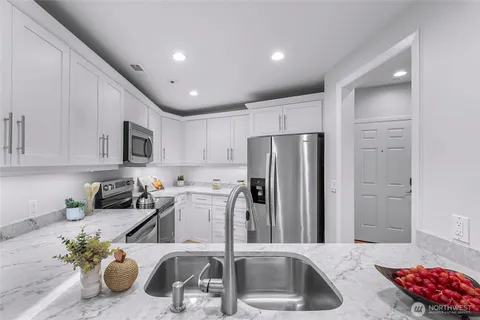 a kitchen with stainless steel appliances granite countertop a sink a stove and a refrigerator