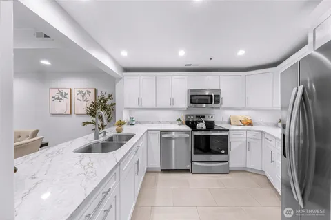a large kitchen with stainless steel appliances granite countertop a sink and dishwasher a refrigerator with wooden cabinets