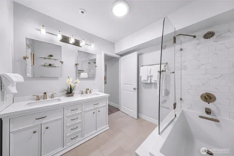 a spacious bathroom with a double vanity sink a mirror a bathtub and shower