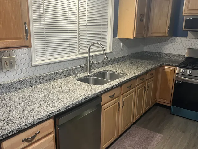 a kitchen with granite countertop a sink and a white wooden cabinets
