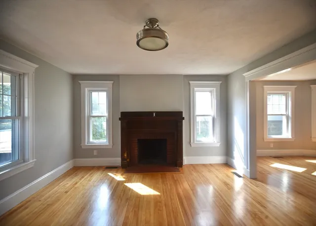 an empty room with windows and fireplace