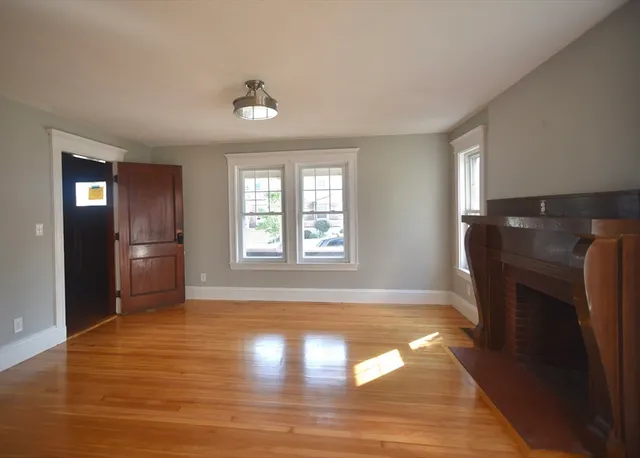 a view of an empty room with window and wooden floor