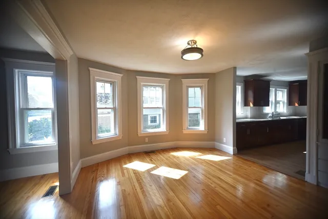 a view of an empty room with a kitchen and wooden floor