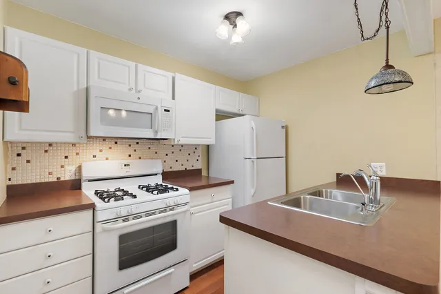 a kitchen with granite countertop a sink stainless steel appliances and white cabinets