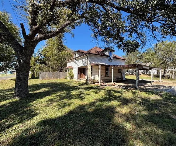 a view of a house with backyard and a tree